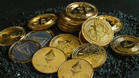 A group of gold cryptocurrency coins on top of black stones